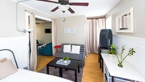 A hotel room with a bed, a desk, a ceiling fan, a sofa, a TV, and a potted plant. - Penthouse @ Palmer Park W/D, AC, Fast WiFi, PrivateRoofDeck in Fabulous Fishtown (Philadelphia)