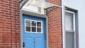 A blue door with a window, a light fixture above, and a small step leading to the entrance. - Penthouse @ Palmer Park W/D, AC, Fast WiFi, PrivateRoofDeck in Fabulous Fishtown (Philadelphia)