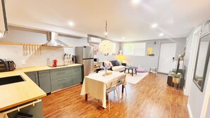A modern kitchen with a dining area, wooden flooring, and a large window providing natural light. - Private Basement + Self Check-in + Kids/Family + Parking (Bedford)