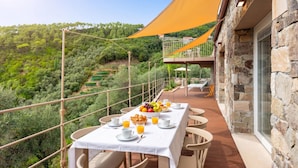 A terrace with a table set for breakfast, overlooking a lush landscape. - Relais Le Torri in Verici Baia Saraceni, Casarza Ligure, Italy (Casarza Ligure)