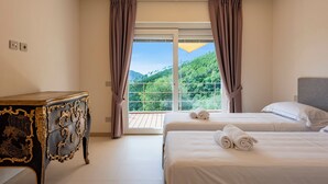 A hotel room with two beds, a dresser, and a large window with curtains. - Relais Le Torri in Verici Baia Saraceni, Casarza Ligure, Italy (Casarza Ligure)