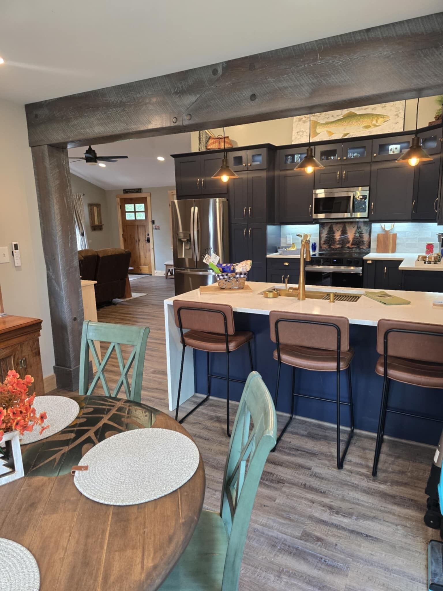 Una cocina moderna con armarios oscuros, electrodomésticos de acero inoxidable y una isla central con taburetes de bar.