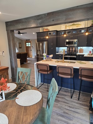 Una cocina moderna con armarios oscuros, electrodomésticos de acero inoxidable y una isla central con taburetes de bar.