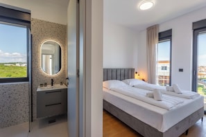 A bedroom with a bed, a bedside table, a mirror, and a window with a view. - Palm Villa Emma with Pool, Medulin, Croatia (Medulin)