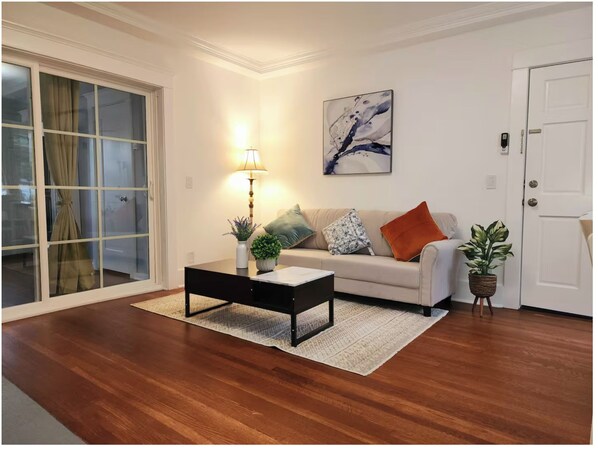 A living room with a sofa, a coffee table, a lamp, and a painting on the wall.