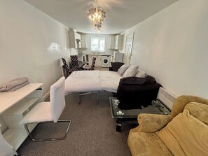 A compact hotel room with a bed, a small table, a sofa, a desk, and a washing machine. - 2 Bed Wolverhampton Apartment-sleeps 5 (Wolverhampton)