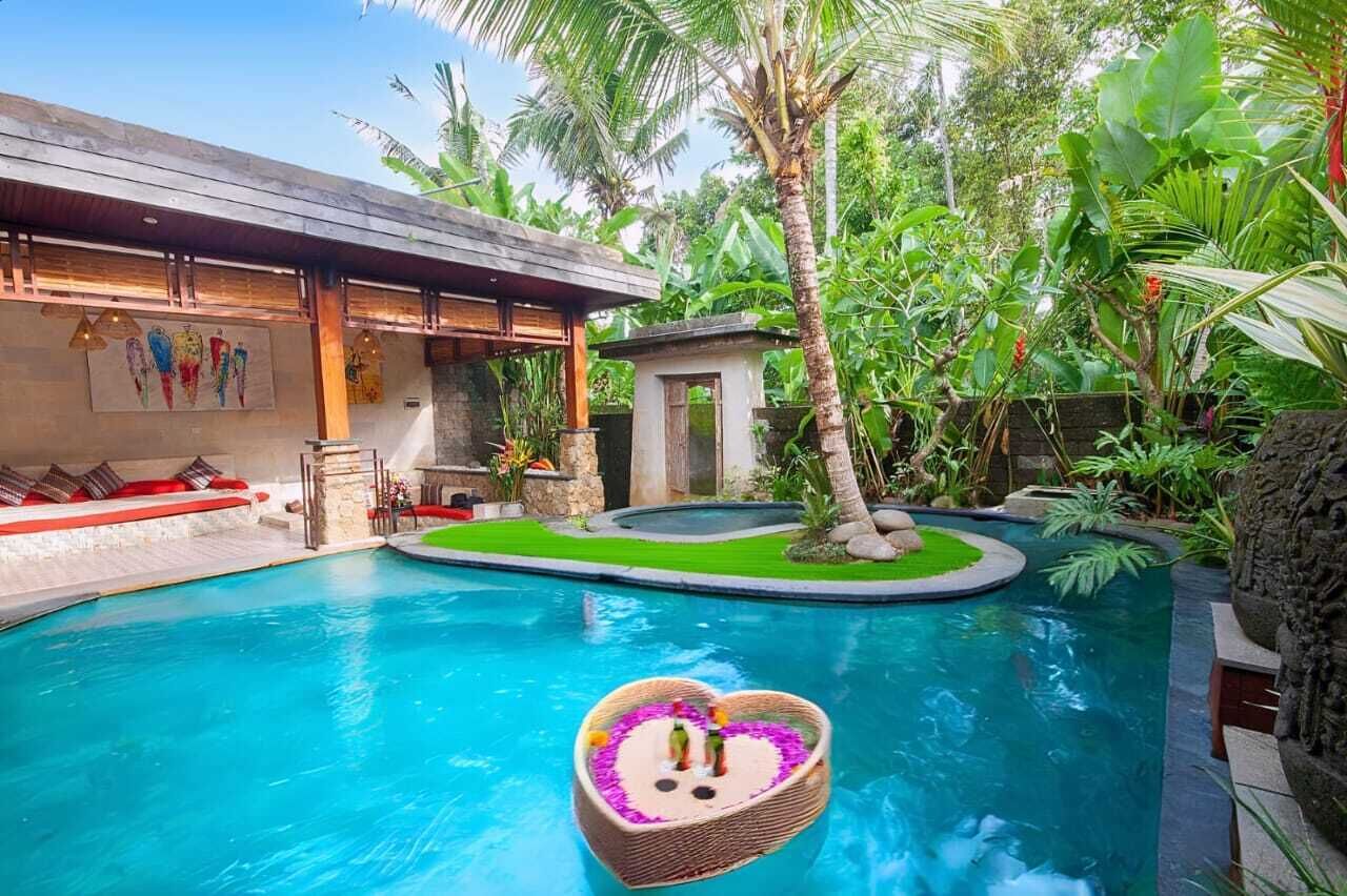 Ein Schwimmbecken mit einem herzförmigen Schwimmer, umgeben von üppiger Bepflanzung und einer Holzkonstruktion.