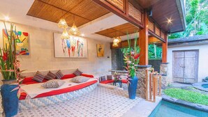 A cozy lounge area with a patterned floor, a seating area with cushions, and a pool. - Nidhi serene villa ubud (Kabupaten Gianyar)