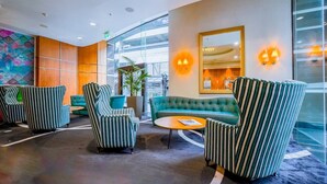 A modern lobby with striped armchairs, a teal sofa, and a round coffee table. - Large Stylish 1BR Apartment + Carpark in CBD (Auckland Central)