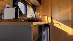 Una cocina pequeña con ventana, estufa y lavamanos.