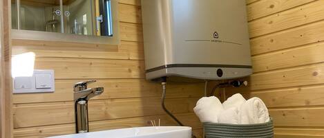 A bathroom with a white sink, a mirror, and a wall-mounted heater.