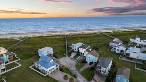 Vue aérienne d’une zone résidentielle côtière, avec des maisons et une plage.