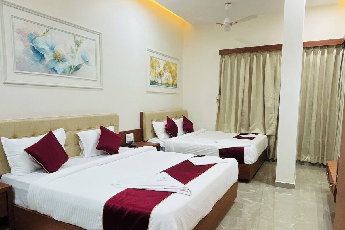 Une chambre d’hôtel avec trois lits, un ventilateur de plafond et un sol en marbre.