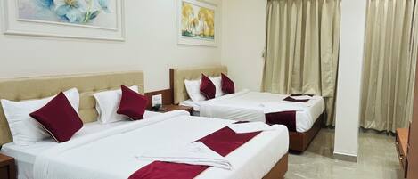 Habitación de hotel con tres camas, ventilador de techo y piso de mármol.