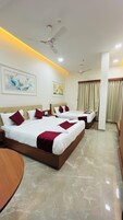 Quarto de hotel com três camas, ventoinha no teto e chão de mármore.