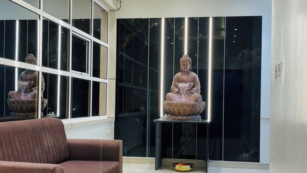 A modern interior with a sofa, a statue, and a reflective wall. - Hotel Park Inn  (Athni)