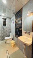 Casa de banho com sanita, bidé, lavatório e chuveiro.