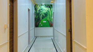 A hallway with a glossy floor, recessed lighting, and a mural of a green pathway. - Hotel Park Inn  (Athni)