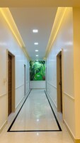 Un pasillo con suelo brillante, iluminación empotrada y un mural de un sendero verde.