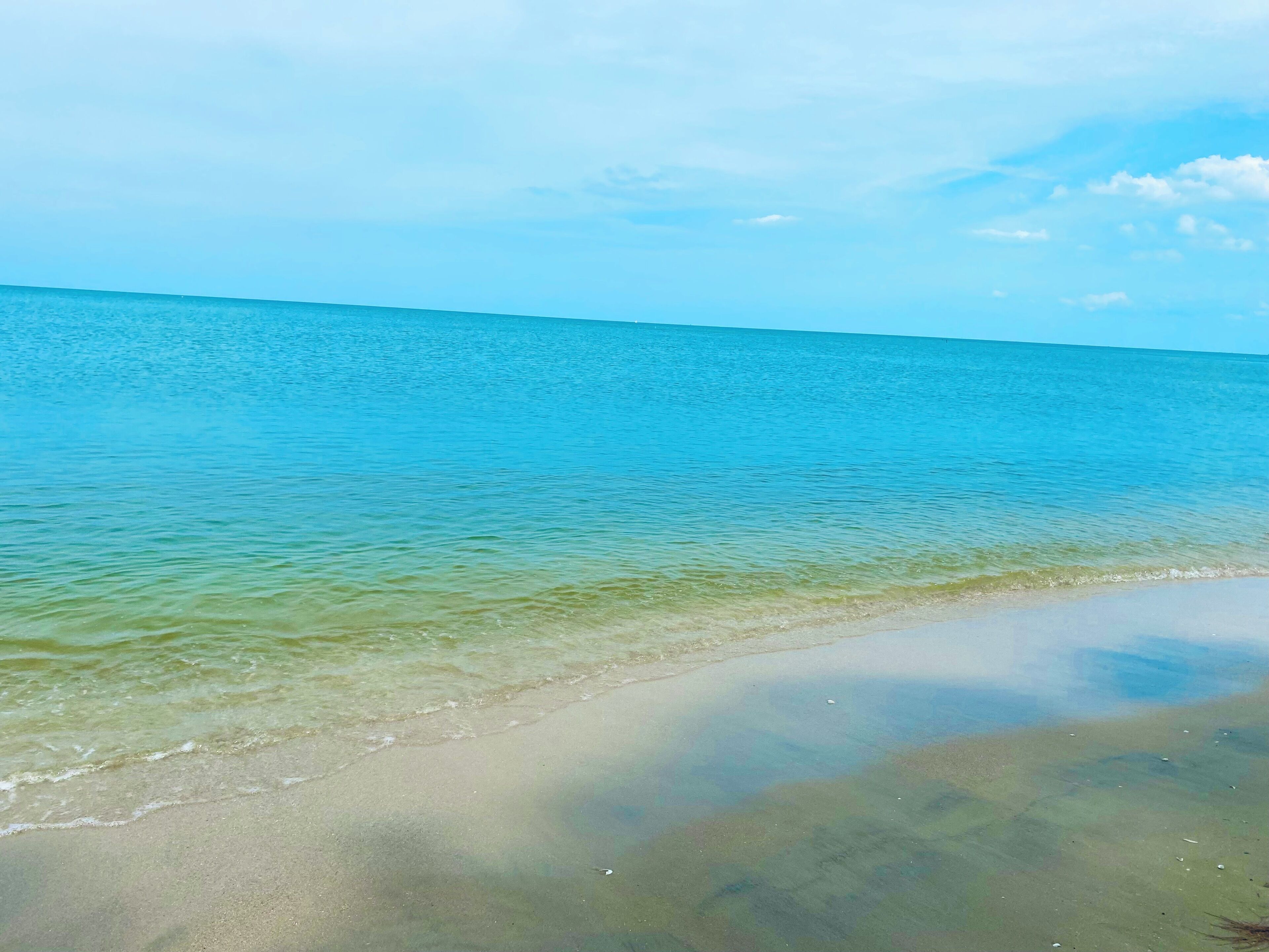 A beach with clear water and a sandy shore.
