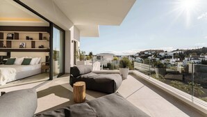 Un balcon moderne avec un canapé, un tabouret en bois et une plante en pot.