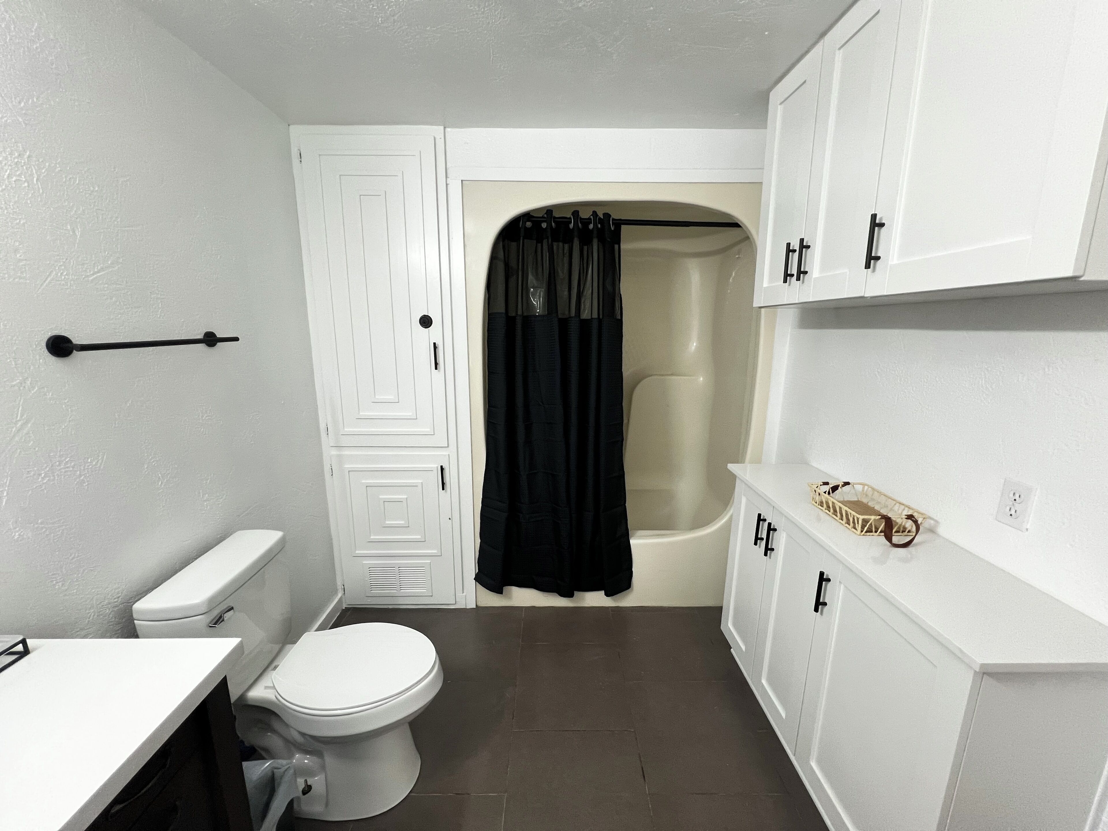 Une petite salle de bain comprenant des toilettes, une baignoire et un meuble de rangement.