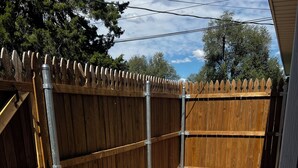 A wooden fence with metal supports, gravel ground, and a clear sky. - Charming studio Backhouse in fantastic Amarillo great quiet neighborhood. (Amarillo)