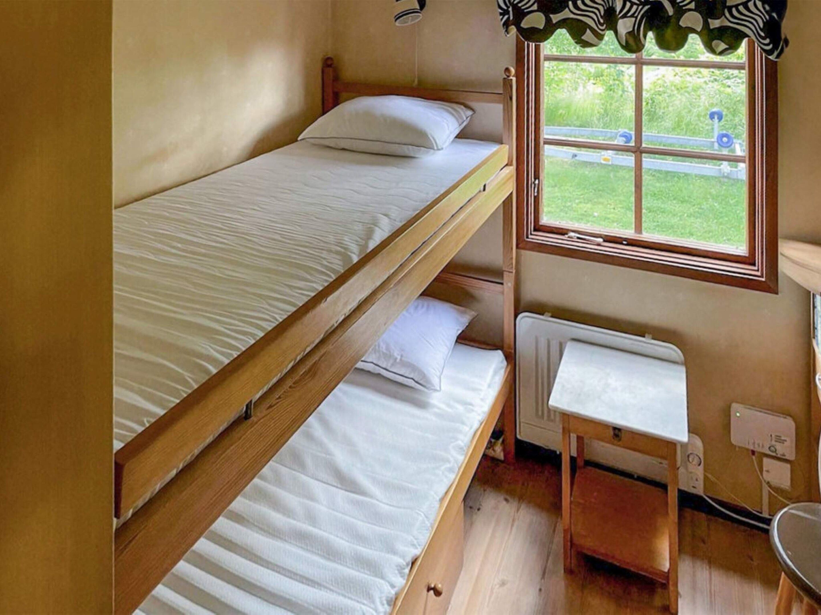 A bunk bed room with a window, a radiator, and a small table.