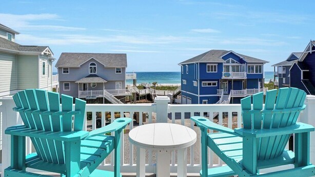 A beachfront property with a white deck, turquoise Adirondack chairs, and a view of the ocean. - New Management Beach, Elevator, Pool, Pet friendly (North Topsaile Beach)