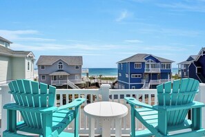 A beachfront property with a white deck, turquoise Adirondack chairs, and a view of the ocean. - New improved "Family Beach Retreat" Elevator, Pool, Pet friendly (North Topsaile Beach)