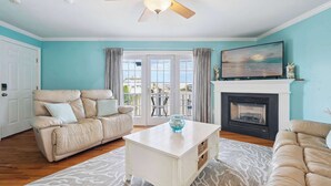 A living room with a beige sofa, a white coffee table, a fireplace, and a ceiling fan. - Rooftop Tide | Ocean Views | Gas Fireplace (Salisbury)