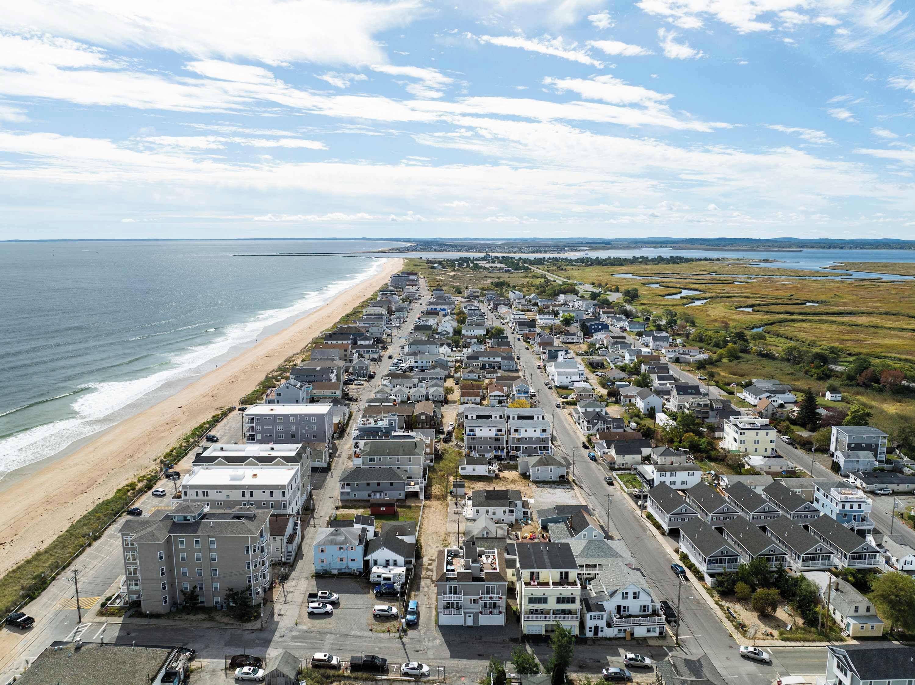 A coastal residential area with a beachfront, rows of houses, and a road leading to the beach.