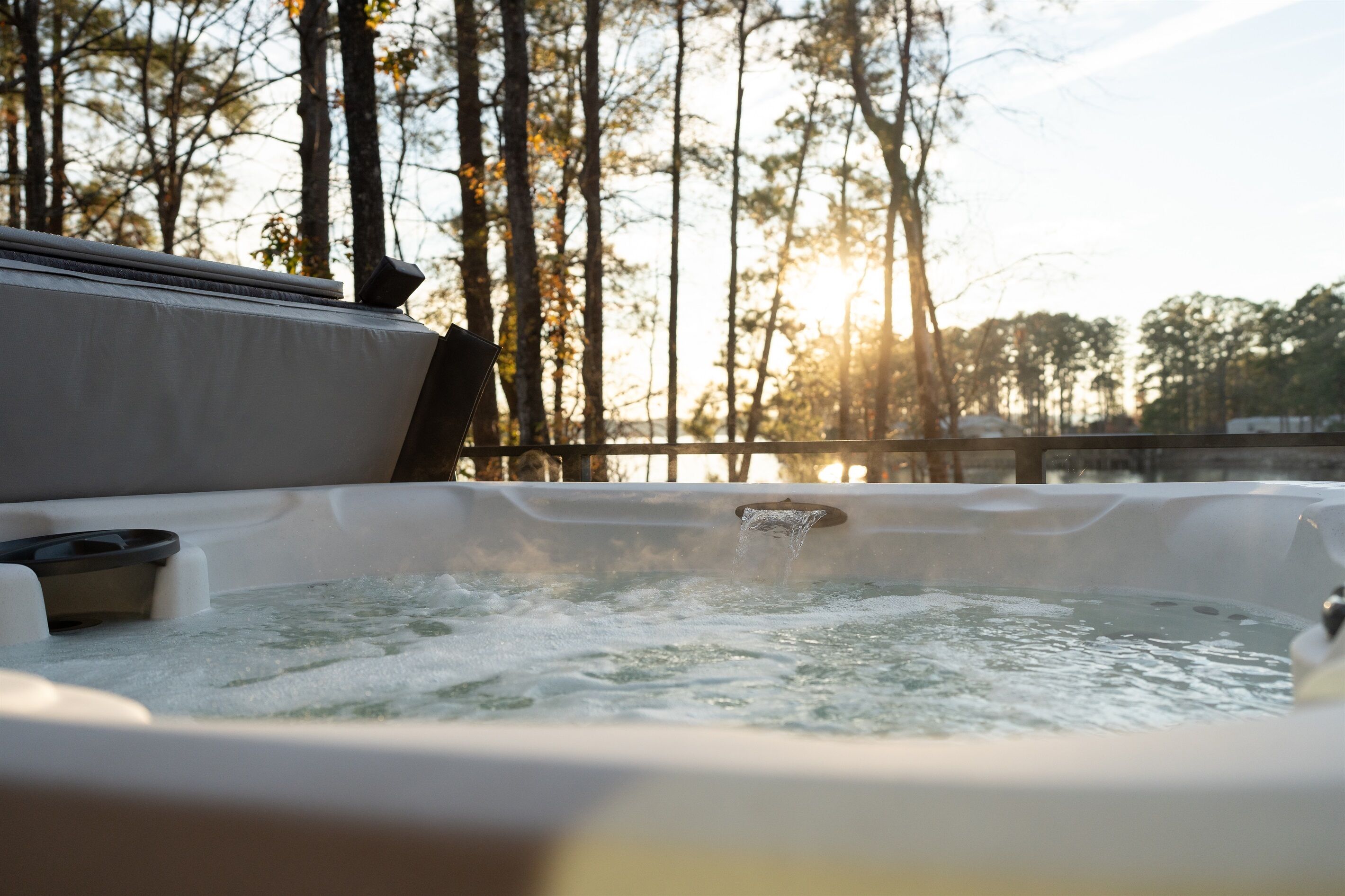 A hot tub with a view of trees and a sunset in the background.