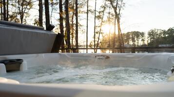 A hot tub with a view of trees and a sunset in the background.