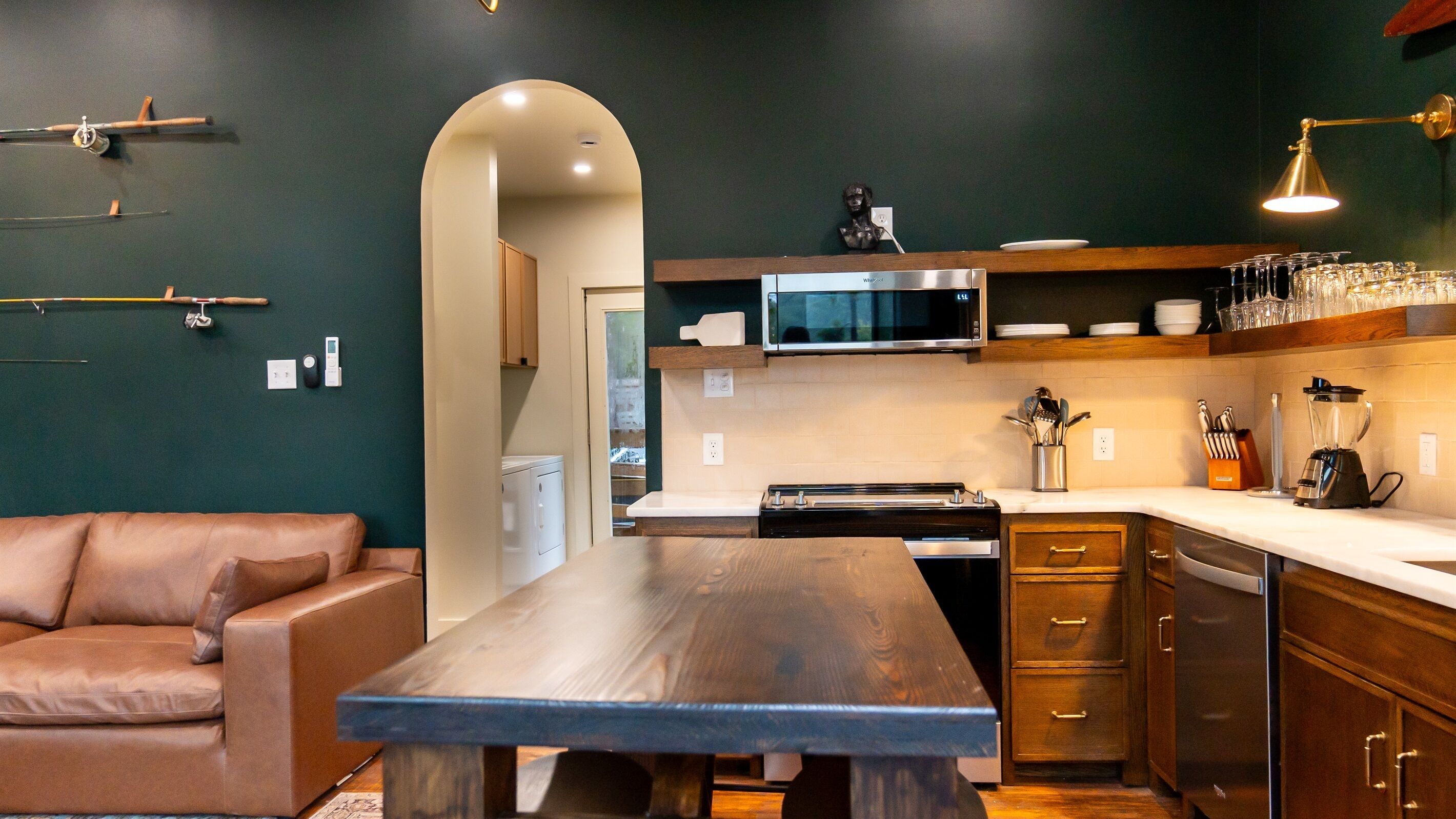 A modern kitchen with a wooden table, dark cabinetry, and a microwave above the counter.