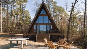 A wooden cabin with a triangular roof, large windows, and a balcony.