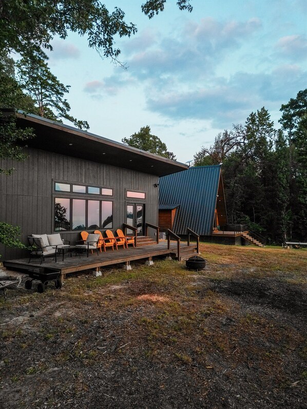 A modern building with a deck, outdoor seating, and a large window.