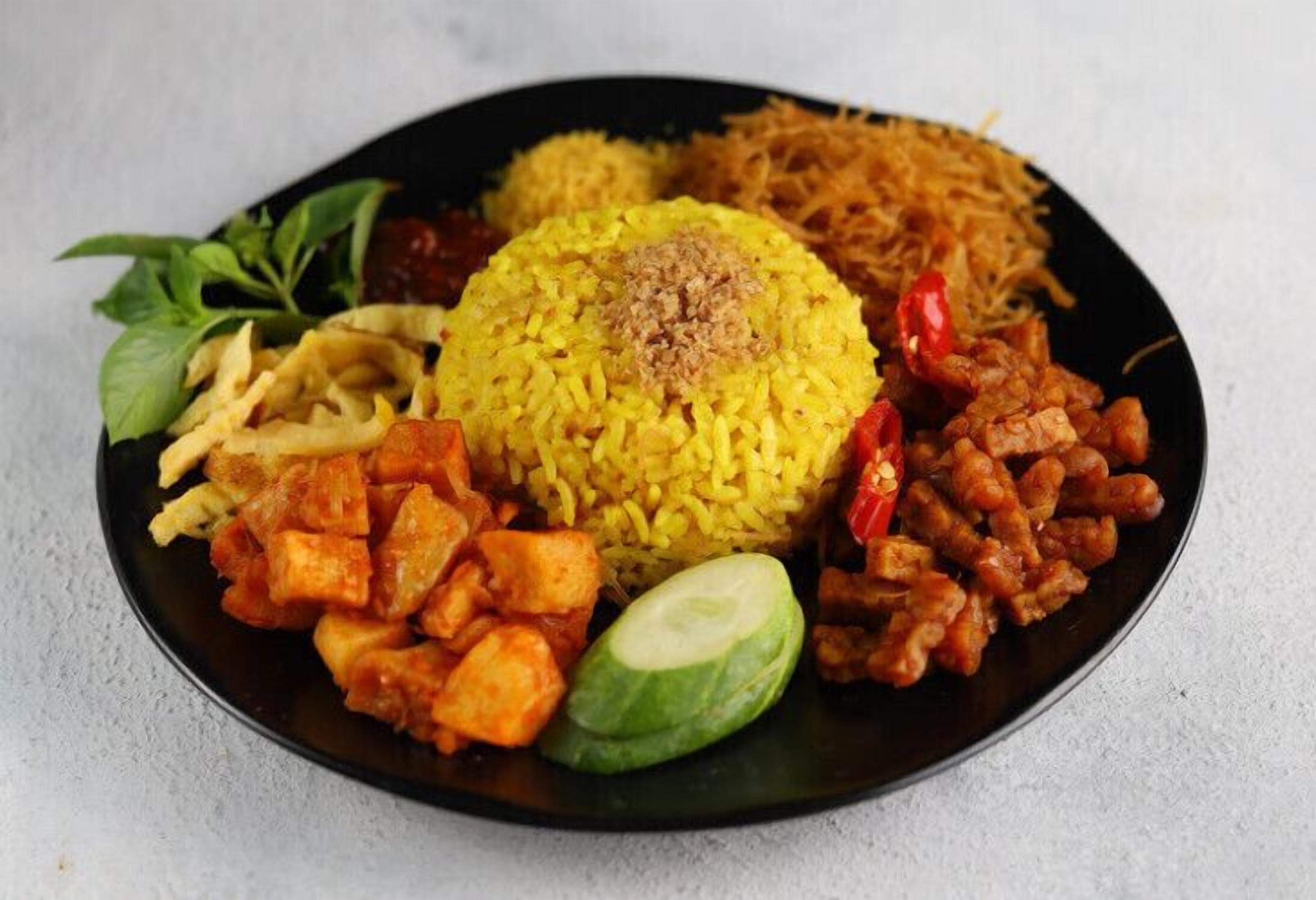 Un plato de comida con arroz amarillo, pollo frito y verduras.