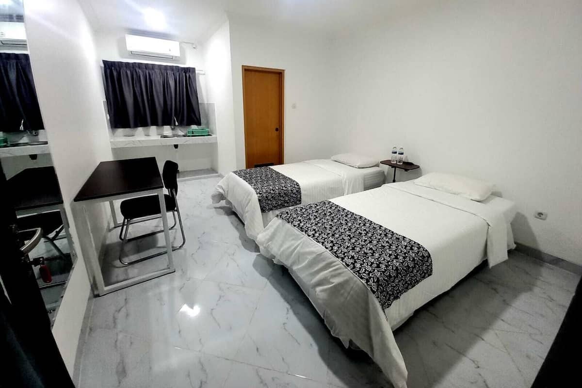 A hotel room with two beds, a desk, and a chair.