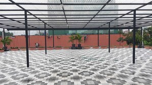 A covered outdoor area with a checkered tile floor, metal beams, and potted plants. - Hotel Wisma Syariah (Jakarta)