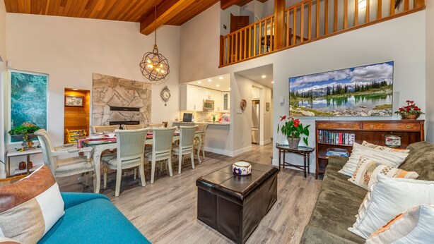 A spacious living area with a dining table, a sofa, and a coffee table. A kitchen is visible in the background. - Telemark 18 - Ski in Walk out,  Short Walk to the Village, New Listing! (Whistler)