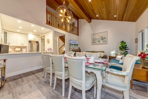 A dining area with a wooden ceiling, a chandelier, and a painting on the wall.