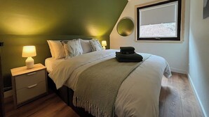 A bedroom with a bed, bedside lamps, a window, and a green accent wall. - 3 bedroom accommodation in Kylesku, near Lairg (Kylesku, near Lairg)