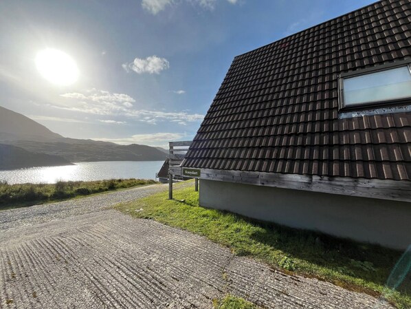 Una casa con tejado de baldosas oscuras, una terraza de madera y un letrero que dice "Knoydart".