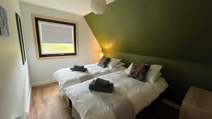 Un dormitorio con dos camas, una ventana, una lámpara de techo y un calentador de pared.
