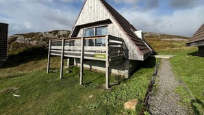 Una cabaña de madera con techo inclinado, una terraza de madera y un letrero que dice "Glenluede".