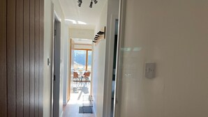 A hallway with wooden flooring leading to a balcony with outdoor seating. - Steall Gorge - UK50495 (Kylesku, near Lairg)