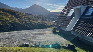 A house with a sloped roof and a view of a mountain in the background. - Steall Gorge - UK50495 (Kylesku, near Lairg)
