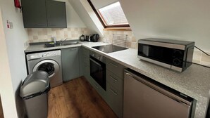 A compact kitchen with a washing machine, a microwave, and a sink. - 3 bedroom accommodation in Kylesku, near Lairg (Kylesku, near Lairg)