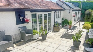 A patio area with wicker furniture, potted plants, and a conservatory with glass doors.
